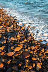 Obraz premium Ocean Waves Wash Over Colorful Pebbles on Bella Vista Beach Shore
