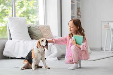 Obraz premium Cute little girl with Beagle dog and book in bedroom