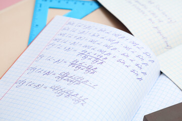 Obraz premium Open copybook with maths formulas and ruler on color table, closeup