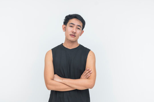 A young filipino male in a tank top stands with arms crossed, looking straight at the camera with a serious expression.