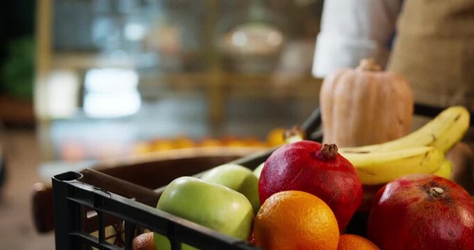 Close up of hand holding fresh nectarine above mixed fruit display with apples bananas oranges and pomegranates. Healthy produce selection in grocery store during daytime