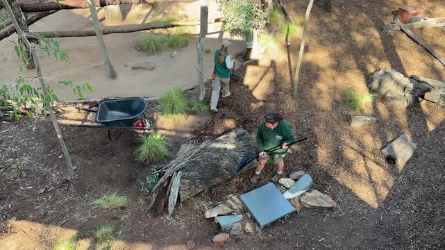 Zookeepers Raking Mulch and Cleaning Animal Enclosure in Dubbo