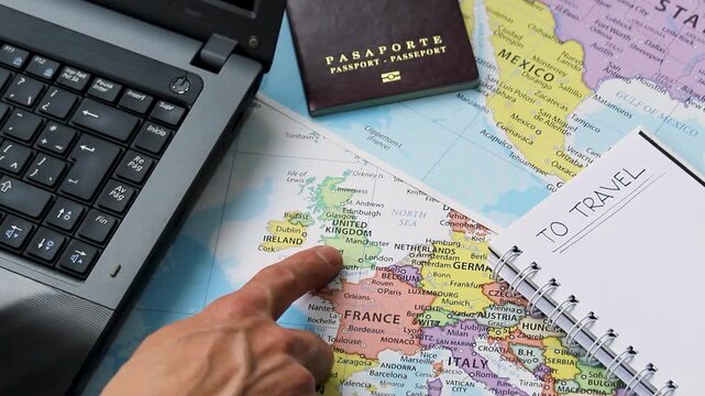 Detailed view of a male hand pointing with his index finger to united kingdom country into a travel concept