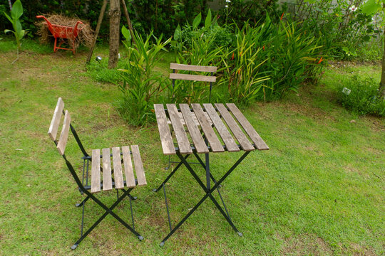 Wooden table and chair set in garden on a sunny day,outdoor seating for restaurant or cafe,Neat paved patio with sitting area and small garden in forest.