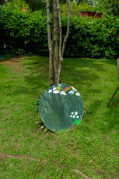 Round mirror with reflection on green grass in forest and big tree,metal round reflecting soft natural light with greenery in park,backyard,fantasy concept,space for text.