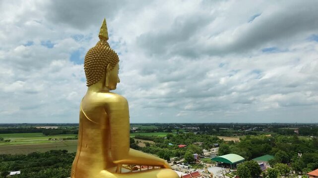 Panoramic aerial view of Thailand's largest Buddha statue, surrounded by rice paddies, in Pathum Thani Province.