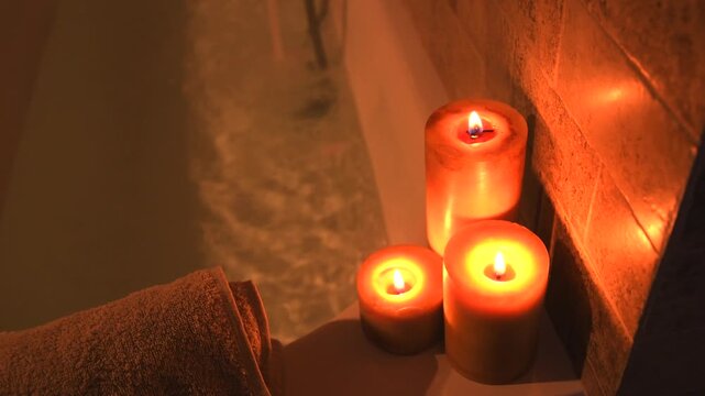 Close up of a relaxing candlelit bath, bubbles on water in jacuzzi bath, warm light from candles creating a peaceful atmosphere.