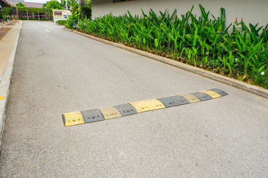 Stripped yellow and black speed bump in the road,Road Speed Bump with Reflective in a sunny day,residential street or parking lot, traffic calming measure to reduce vehicle speeds concept.
