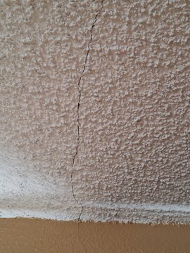 Textured popcorn ceiling with a visible crack
