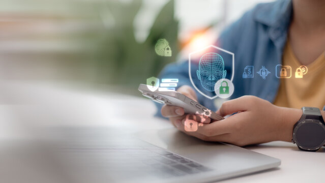 Person using smartphone with facial recognition biometric security holographic icons. Cyber security, data protection, and deepfake prevention technology concept in business.