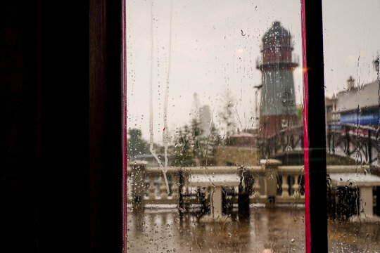 Raindrops trickle down the glass,Water Droplets on a pane of glass with blurred city background,View from a window showing rain falling rainy day,Copy space.