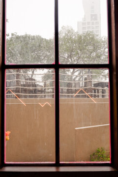 Raindrops trickle down the glass,Water Droplets on a pane of glass with blurred city background,View from a window showing rain falling rainy day,Copy space.
