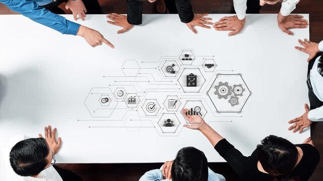 A diverse business team engages in strategic discussion around a table with technological visuals, promoting collaboration and inspiring innovative solutions. Raster