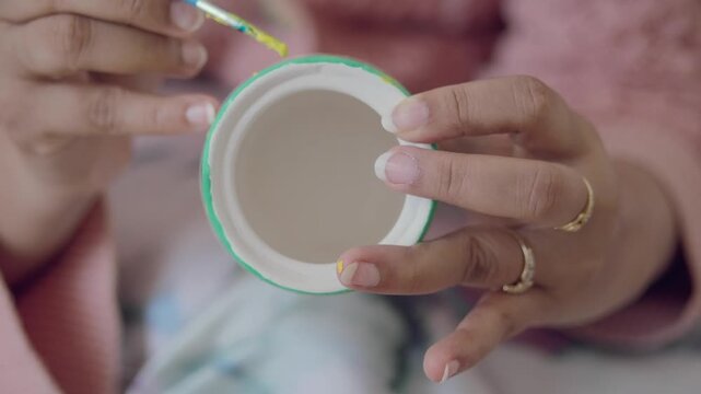 Painting a design on a small round container