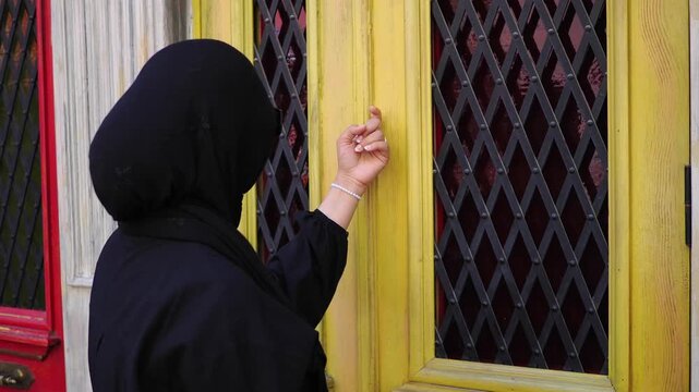Woman knocks on a yellow door in a lively neighborhood