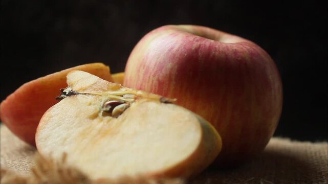 whole red apple with a sliced half on a black background