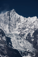 Naklejka premium Steep Snow-capped Mountain Ridge and Giant Valley Glacier, Raw Alpine Mountain Texture Under Deep Blue Sky