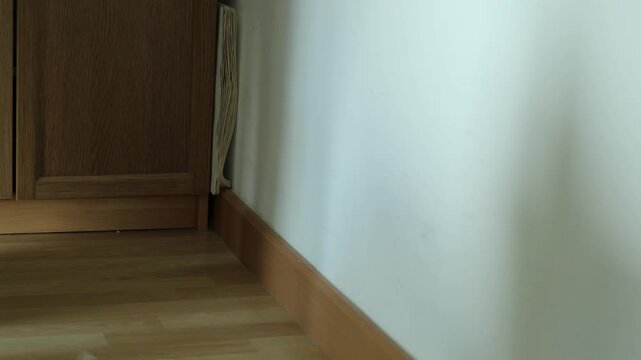 Horizontal 4K footage of a man picking up a backless wooden stool next to a bookshelf and carrying it away leaving empty room space