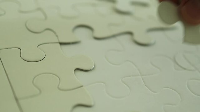 Horizontal 4K video showing male fingers placing blank white puzzle pieces into open slots only to find they do not fit