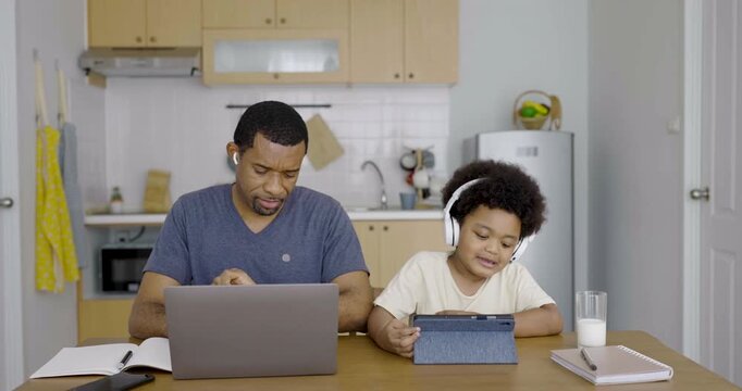 Smile father young toddler son wearing headphones using laptop together online learning and family bonding at home. Freelance work remote single dad lifestyle
