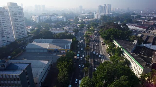 Drone flying towards, a two way big avenue behind and in the horizon the city of S&atilde;o Paulo with morning fog at"Ponte do Socorro"