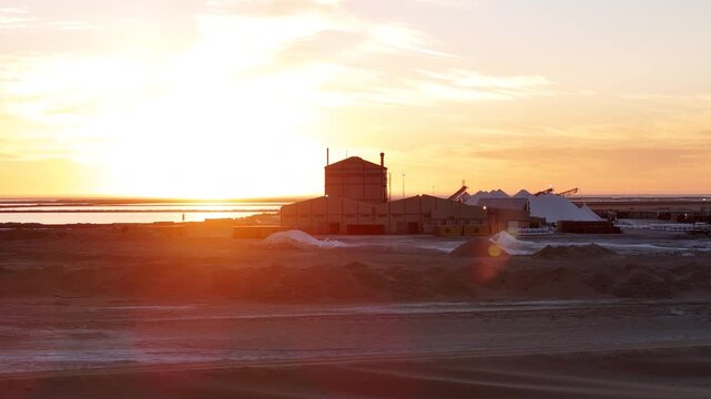 Setting sun disappears behind salt factory and reappears. Walvis Bay, Namibia