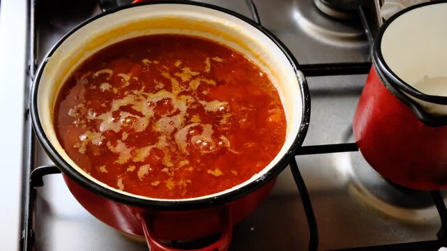 The pot of apricot jam boiling on the stove