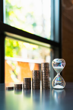 Stacked coins growth graph with sandglass timer, concept for long term investment financial planning time management money saving goal.