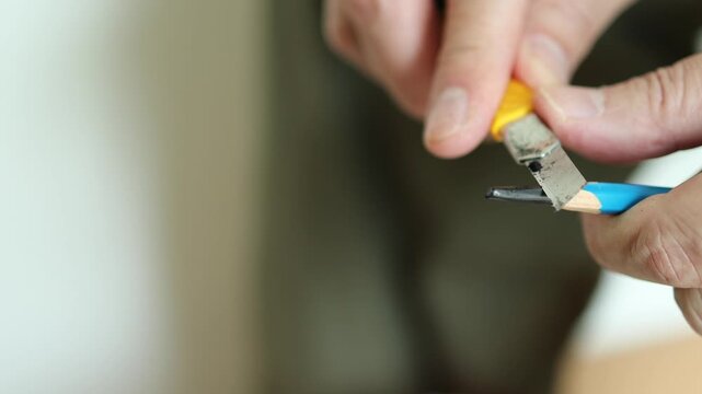 Horizontal 4K alternate angle shot of male hands carefully whittling and scraping an EE pencil lead, releasing fine graphite dust particles