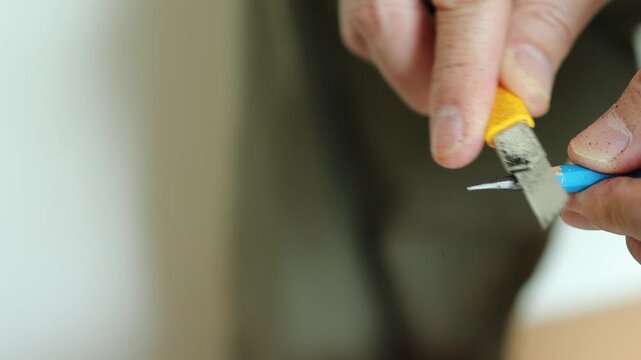 Horizontal 4K video of a professional artist inspecting a newly sharpened needle-point EE pencil lead and retracting the utility blade safely
