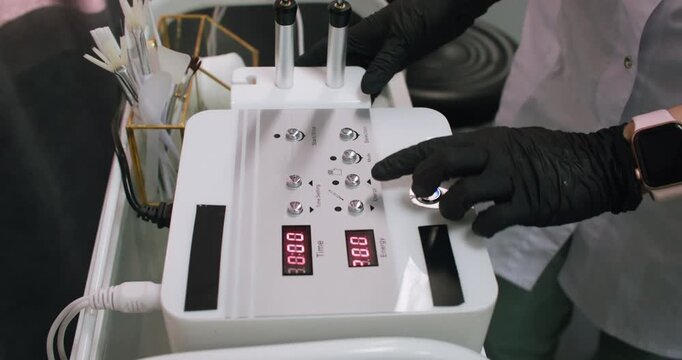 Microcurrent machine. Beauty tool. Unrecognizable female master hands using skincare equipment for professional anti-aging procedure.