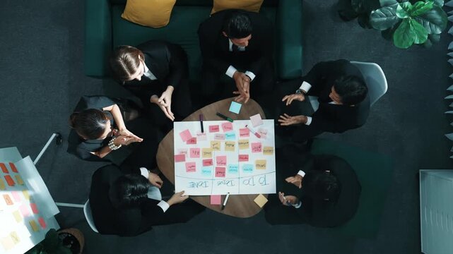 Top down aerial view of people putting hands together and clapping hands to celebrate successful project while using mind map to brainstorm idea. Skilled team stacking hands together. Directorate.