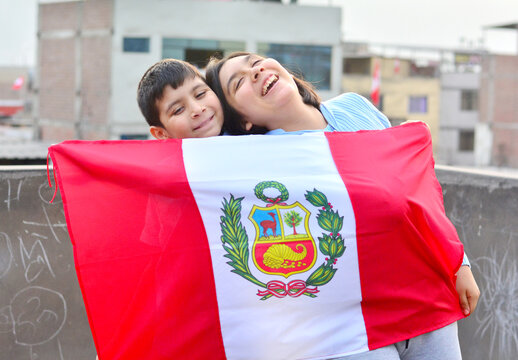 Two happy kids holding peruvian flag.
