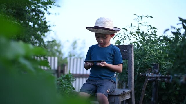 4 Year Old ASEAN Boy Using Tablet in Vegetable Garden Exploring Smart Farming AI Technology and Future Food Security Concept
