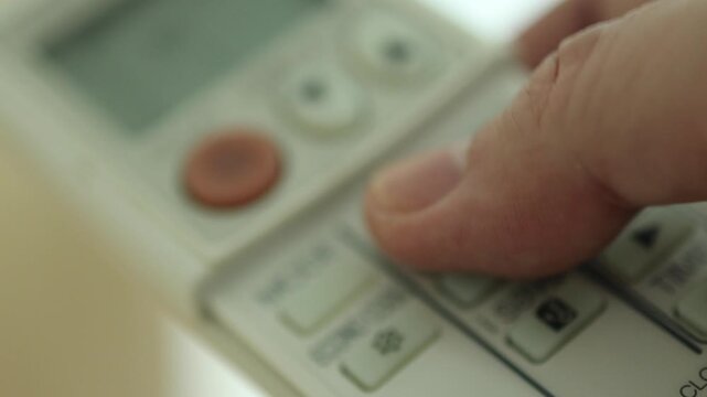 Horizontal 4K close up video of a man hand opening air conditioner remote cover, pressing buttons to change fan speed and mode, then closing cover