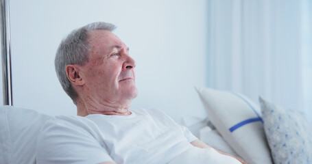 Fototapeta premium Thinking, old man and rest in bed at hospital, medical results and recovery for chronic illness. Sad, senior person and vision at facility for bad news, cancer diagnosis and geriatric rehabilitation