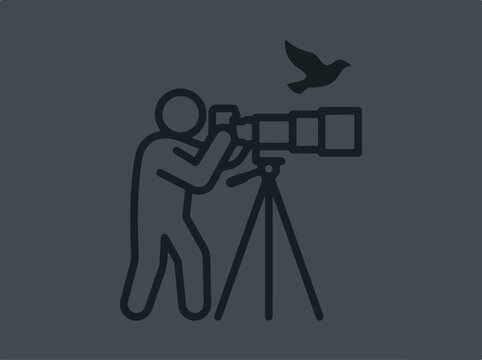 Photographer with telephoto lens on tripod capturing flying bird