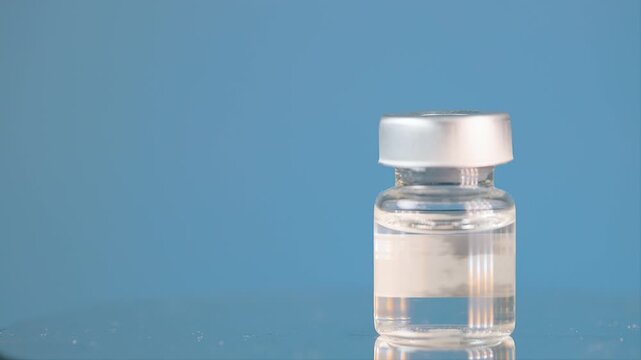 Hopeful medical nad plus therapy wellness treatment with clear glass vial bottle of liquid medicine on blue background, reassuring health concept
