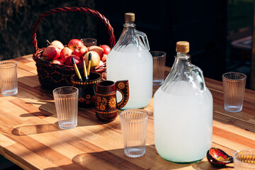 Traditional Russian beverage in glass jugs and apples on wooden table © Sergei