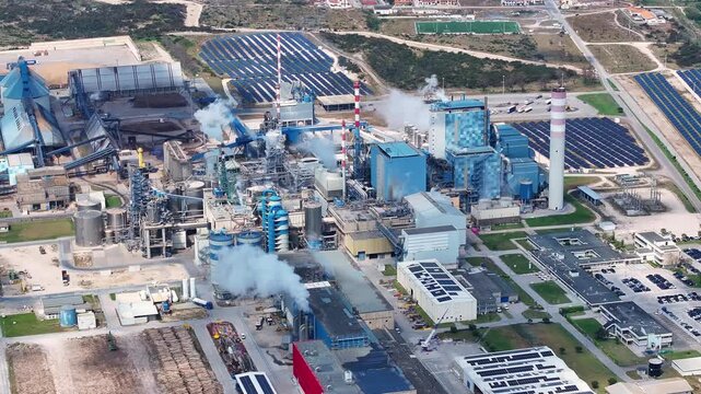 Extensive industrial complex featuring a pulp and paper mill alongside a biomass facility with solar panels, producing renewable energy