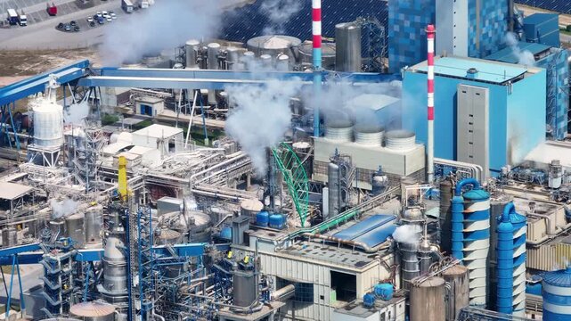 Aerial view of a large pulp and paper mill with a biomass power plant. The industrial complex shows smokestacks emitting steam