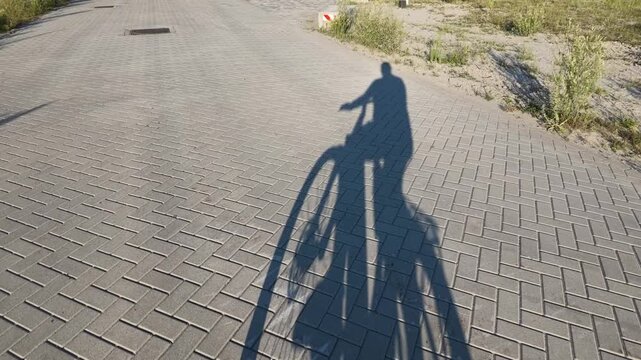 Long shadow of a cyclist moving on a paved road