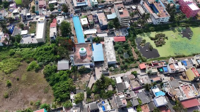 Cinematic aerial view of Kovalam Dargah nestled within the coastal village. The mosque's distinctive dome and minarets are surrounded by residential neighborhoods, lush greenery, and ponds.