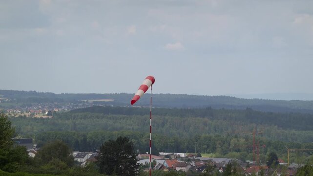 Ein Windsack bewegt sich sanft im Wind mit einer weiten Landschaft im Hintergrund