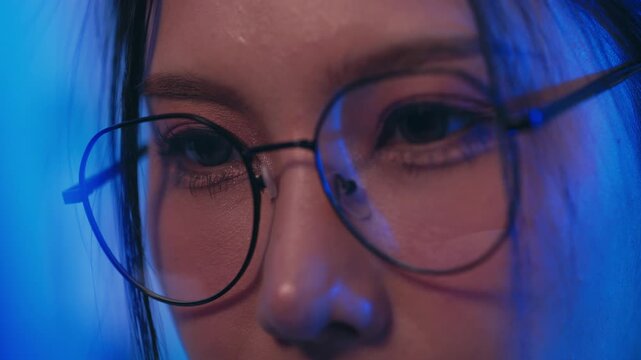 Woman eyeglass face portrait closeup blue light eye eyelash reflection calm gaze round eyewear skin texture soft shadow neon color studio mood modern detail
