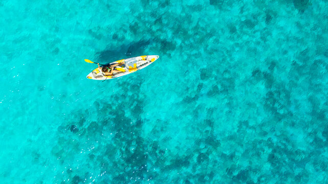 Aerial view of a woman and a young man kayaking on clear blue waters at Andaman Island. She does water sports activities	
