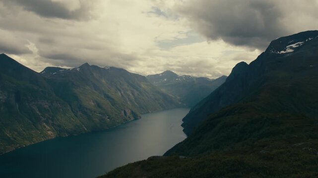 High Liavarden viewpoint looks down along a long blue fjord enclosed by tall rugged ridges on an overcast day.