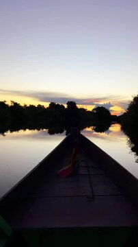 Traditional wooden boat navigation at dusk in Bolivian Amazon