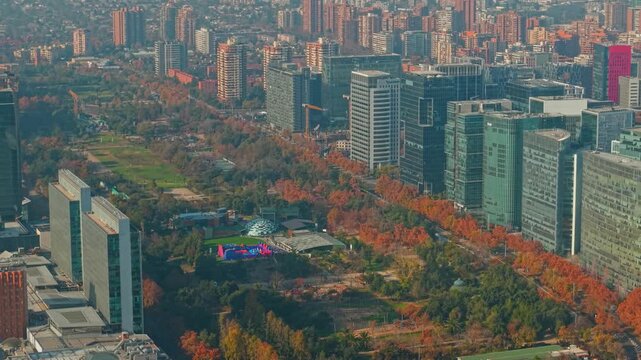 Aerial telephoto orbit of Araucano Park in Las Condes, Santiago, Chile, with a light mist and autumn-colored trees