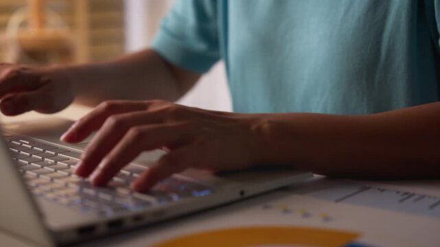 Close-up of female hands typing on laptop keyboard.